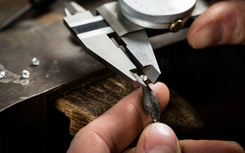 Close-up of a jeweler using a digital caliper to measure a lab grown diamond.