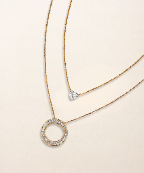 Layered gold necklaces featuring a diamond heart pendant and a diamond-encrusted circle pendant